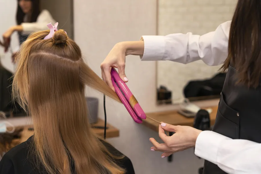 Stylist straightening a client's hair in a salon